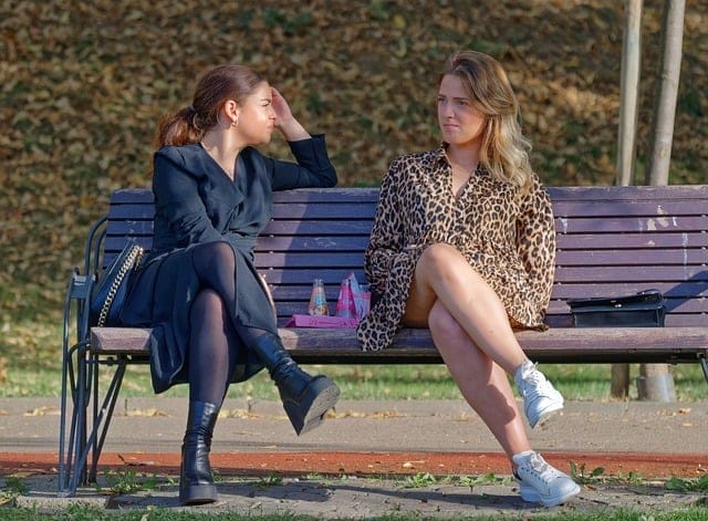 Two women talking while sitting on a park bench